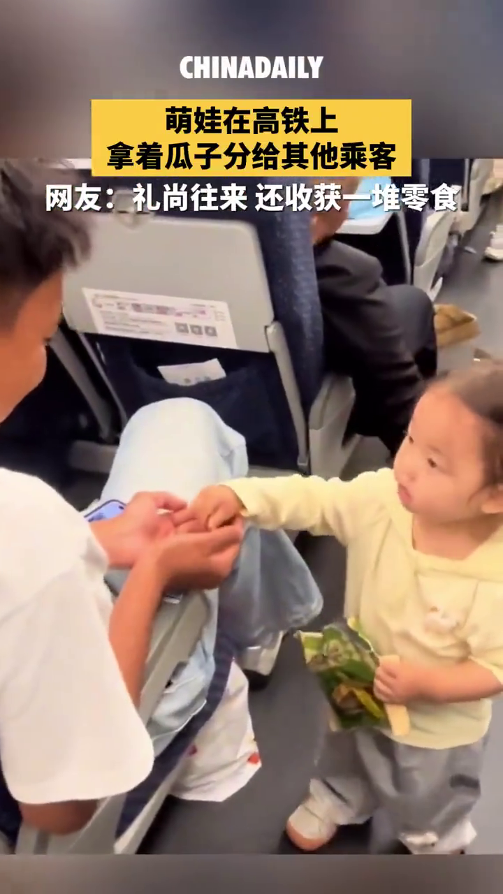 萌娃在高铁上拿着瓜子分给其他乘客 。网友：收获一堆零食