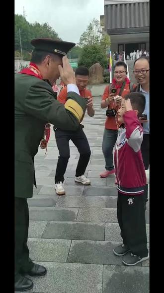 2026年9月18日，金寨希望小学，小男孩请功勋老兵胡国桥签名。签完，老兵俯身蹲下递上，孩子接过签名