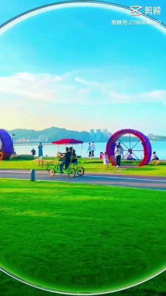 谁懂啊！海边草坪上踩着双人脚踏车🚴‍♂️，红伞一撑，微风拂面～巨型彩虹轮毂装置太出片📸，随手一拍就是
