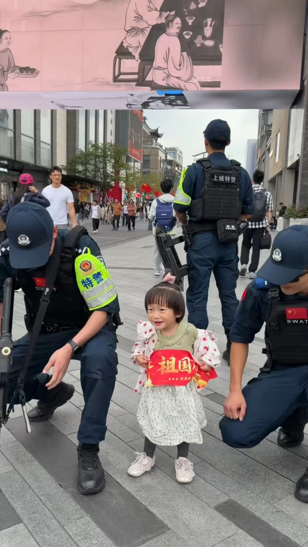 特警哥哥主动蹲下来和小朋友合影，帮助拉红