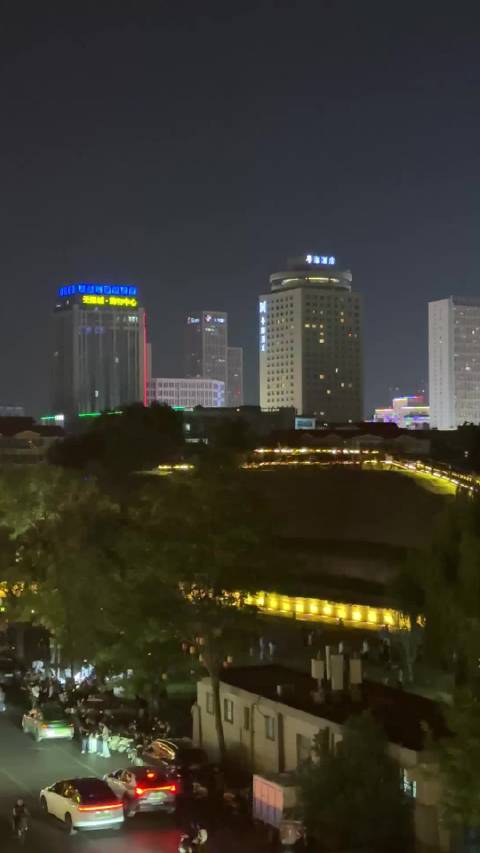 郑州城墙夜景实拍，开放后非常热闹，城墙上人流如织。远处的高楼大厦此起彼伏，繁华大都市的味道越来越浓
