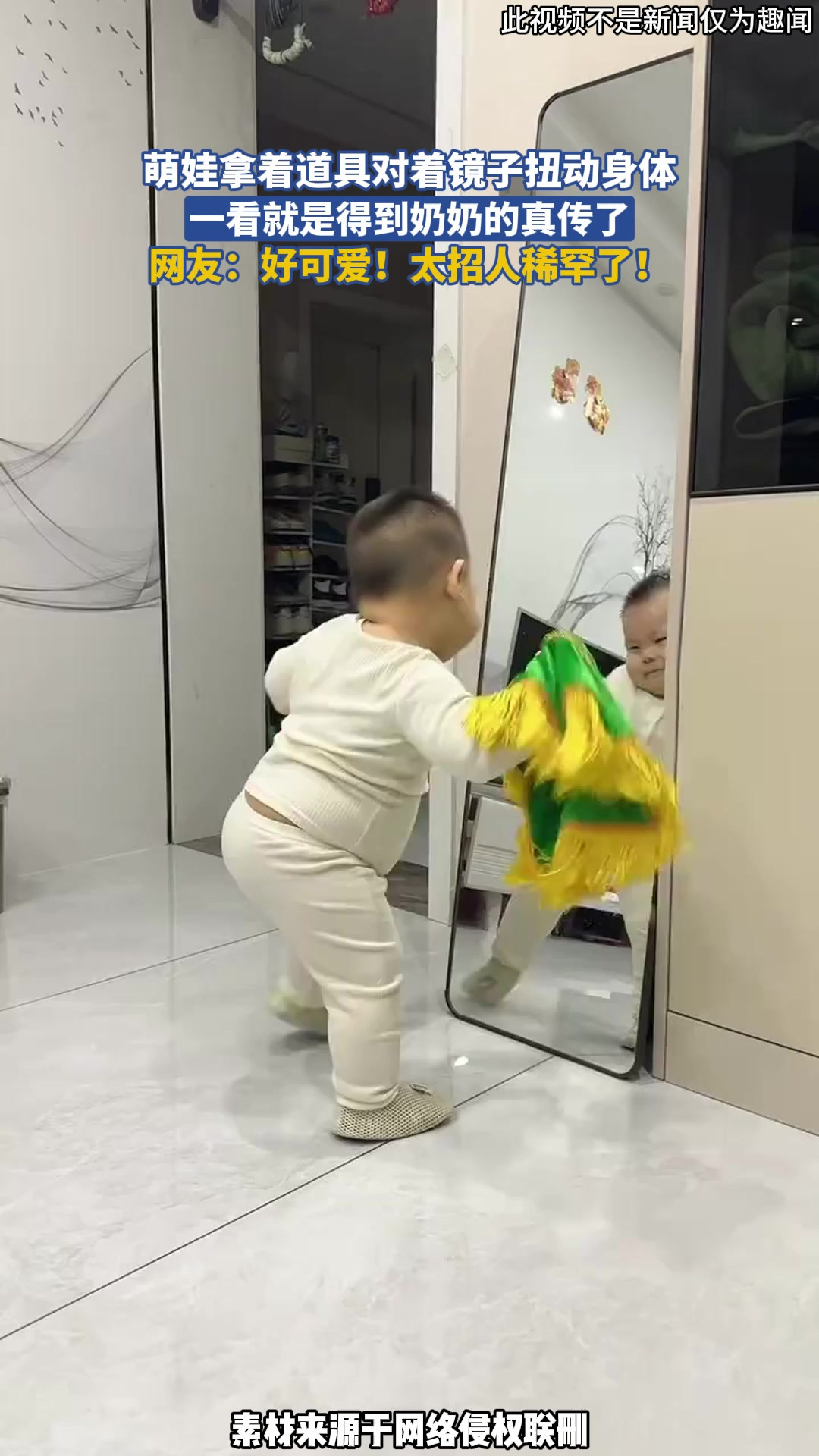 萌娃拿着道具对着镜子扭动身体，一看就是得到奶奶的真传了