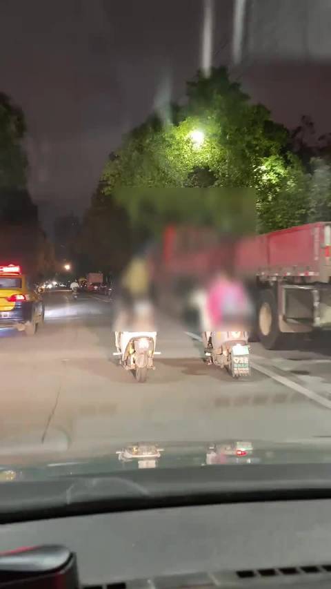 两女子骑电动车并排骑，一边骑一边聊天，龟速挡道